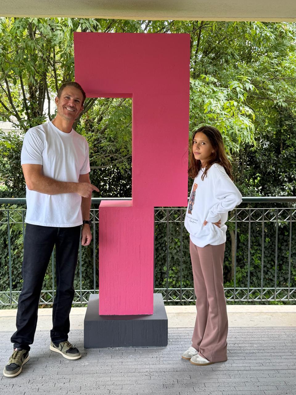 Escultura geométrica rosa en un entorno verde